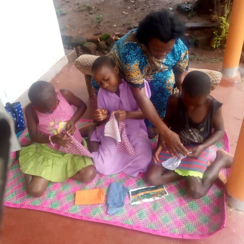 A mentor guiding girls as they learn to sew together